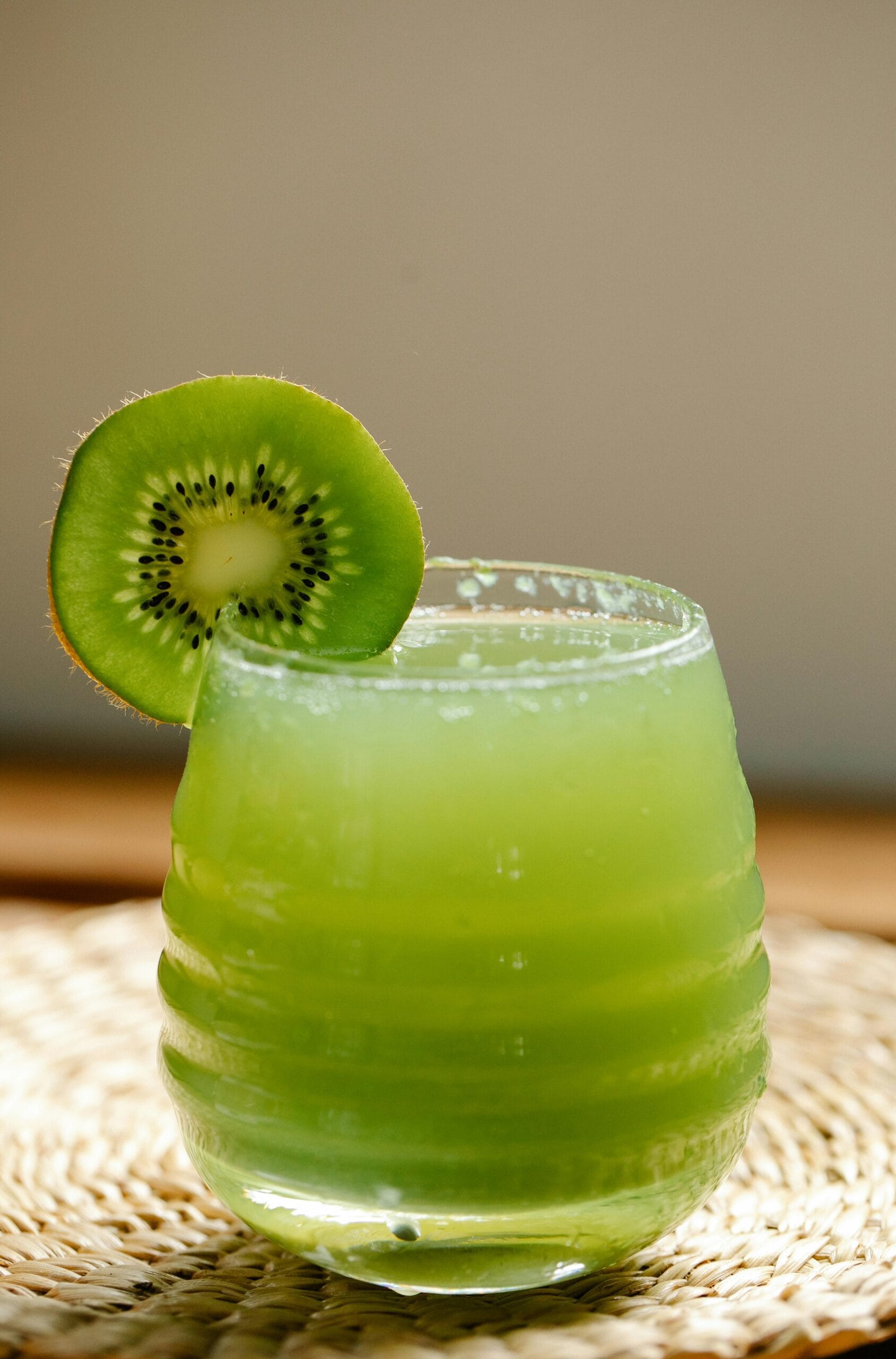 A vibrant glass of kiwi juice with a fresh kiwi slice, perfect for a refreshing drink on a sunny day.